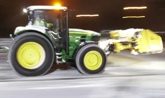 A tractor driving down the road at night.